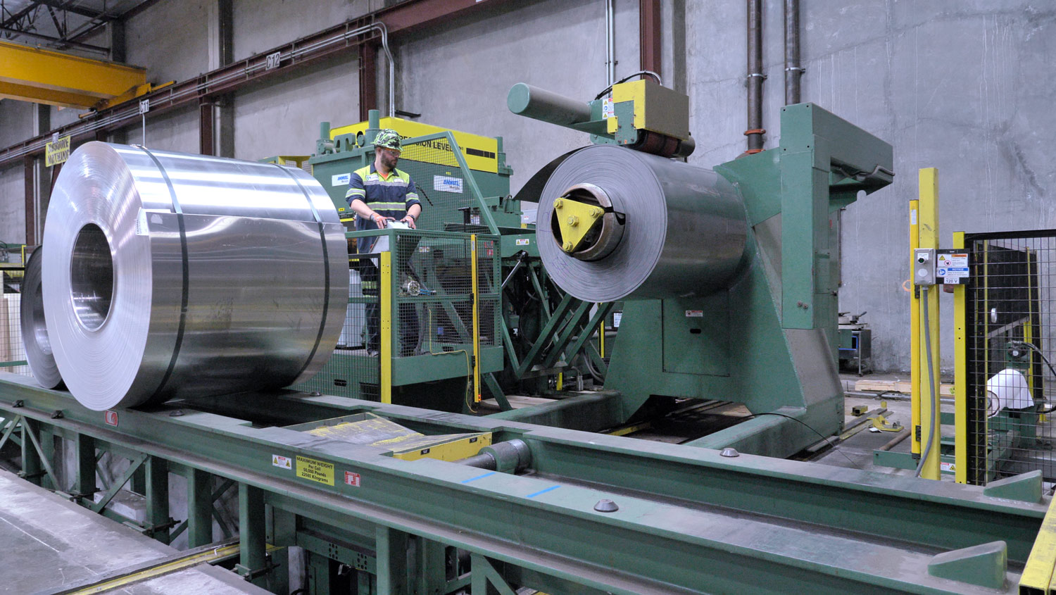 Steel Coil Cut into Sheets” alt: “Steel coil is shown going through a sheet cutting machine.