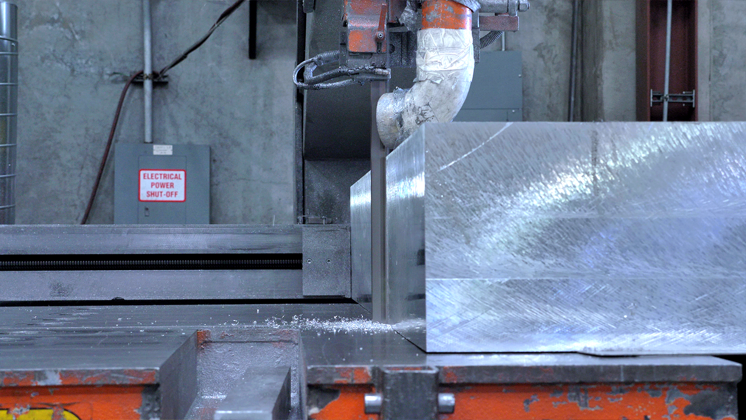 A very thick steel plate is sawed on a table